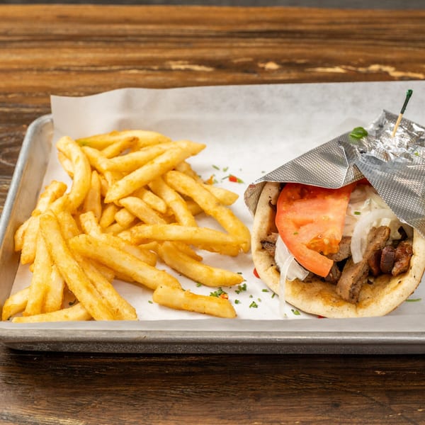 A gyro wrapped in foil with a side of golden french fries on a metal tray.