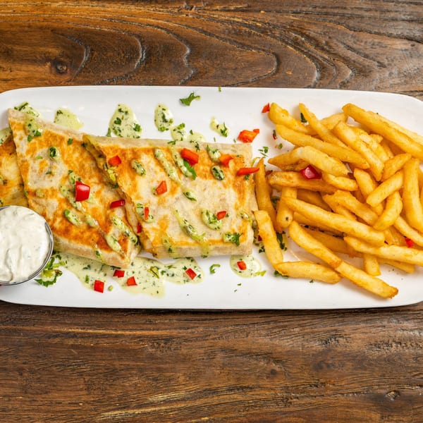 Quesadillas drizzled with green sauce and red peppers, served with fries and a side of white dip.
