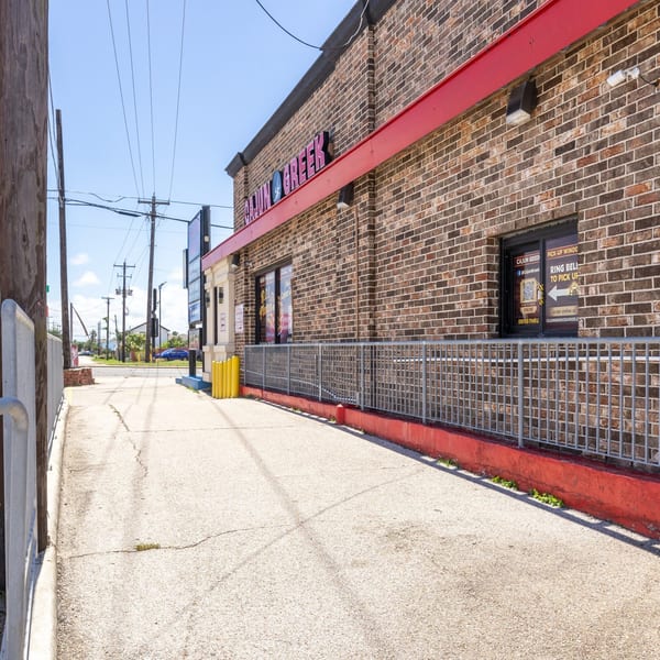 Exterior view of Cajun Greek restaurant with a brick facade, red trim, and a sidewalk leading to the entrance.